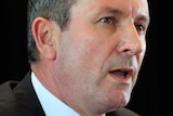A tight head shot of WA Premier Mark McGowan speaking during a media conference against a black backdrop.