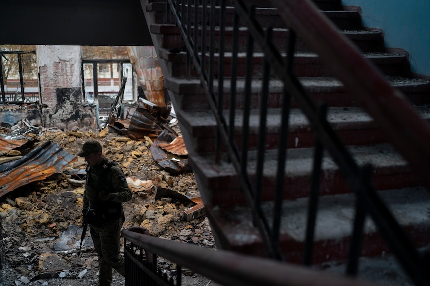 A Ukrainian serviceman walks over debris in a heavily damaged school at the recaptured town of Lyman.