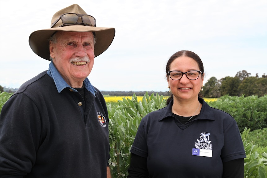 A man and a women stand in front of a canola crop