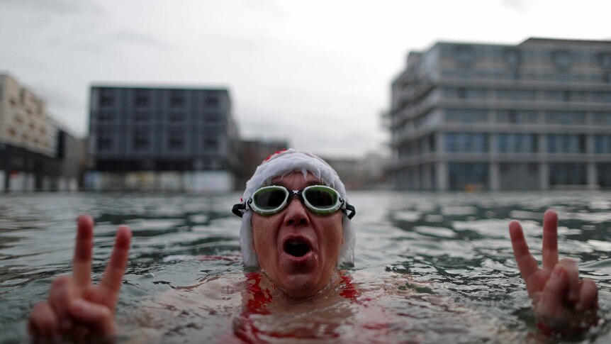 A winter swimmer wearing a Santa Claus hat enjoys a bath in the 5 degree water of the Canal de l'Ourq in Pantin, outside Paris, France.