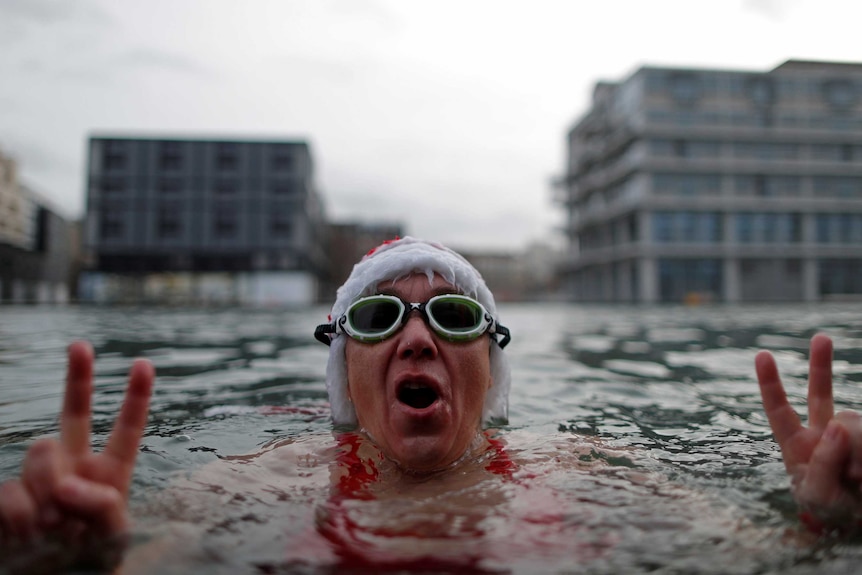 A winter swimmer wearing a Santa Claus hat enjoys a bath in the 5 degree water of the Canal de l'Ourq in Pantin, outside Paris, France.