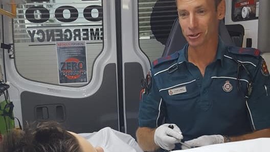 A boy lays in the back of an ambulance while a paramedic is beside him.