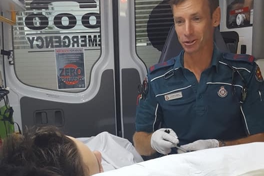 A boy lays in the back of an ambulance while a paramedic is beside him.