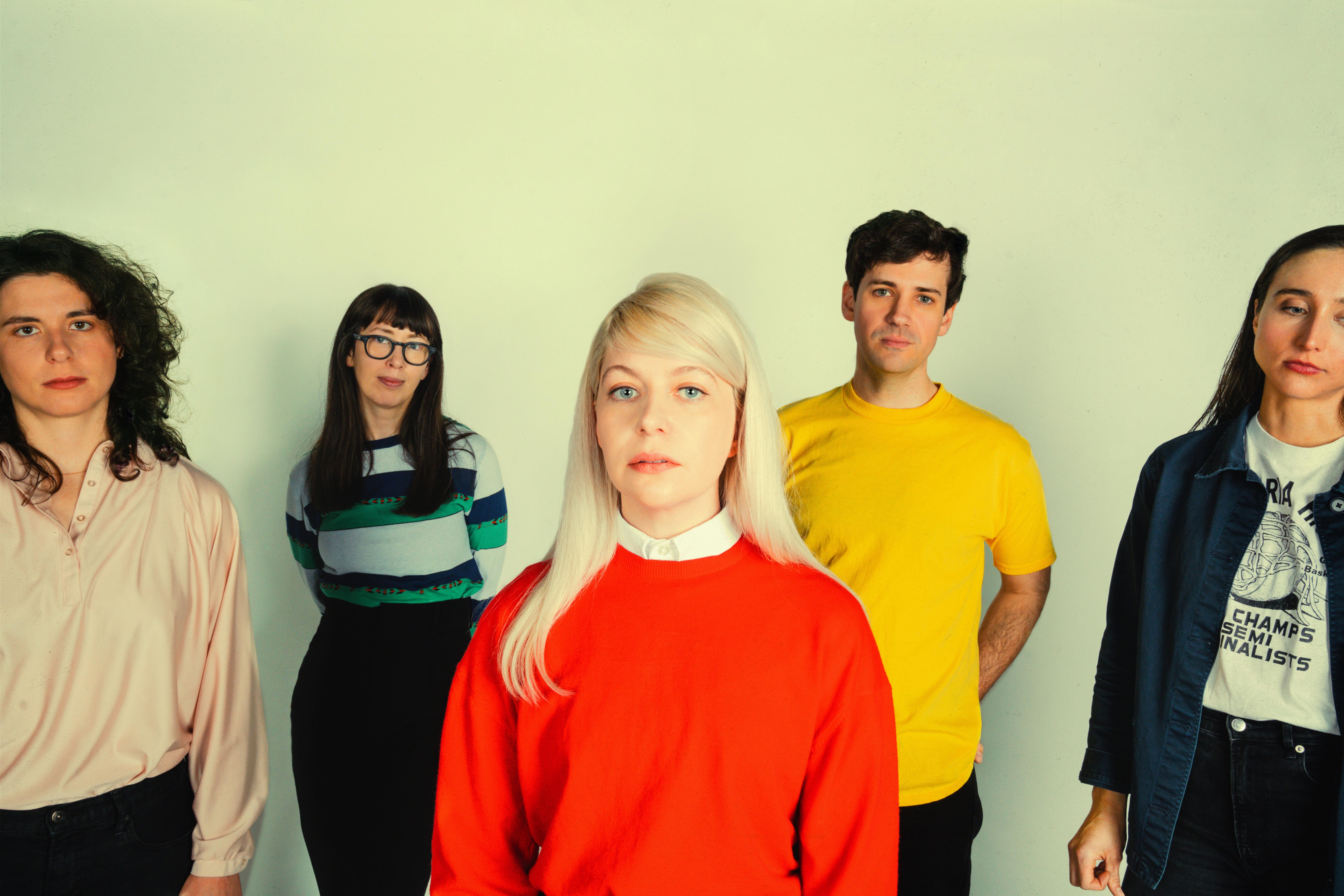 Five members of a band pose inside a photography studio.