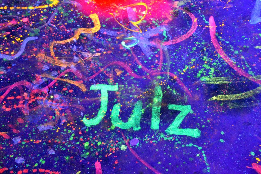 "Julz" written on the floor in neon paint at Julian Scharf's party.