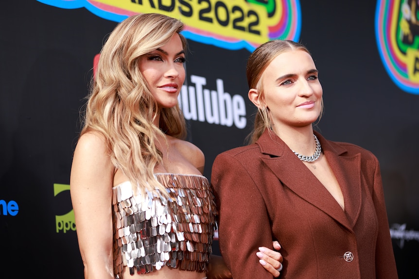g flip and chrishell stause stand arm in arm posing for pictures on the arias red carpet