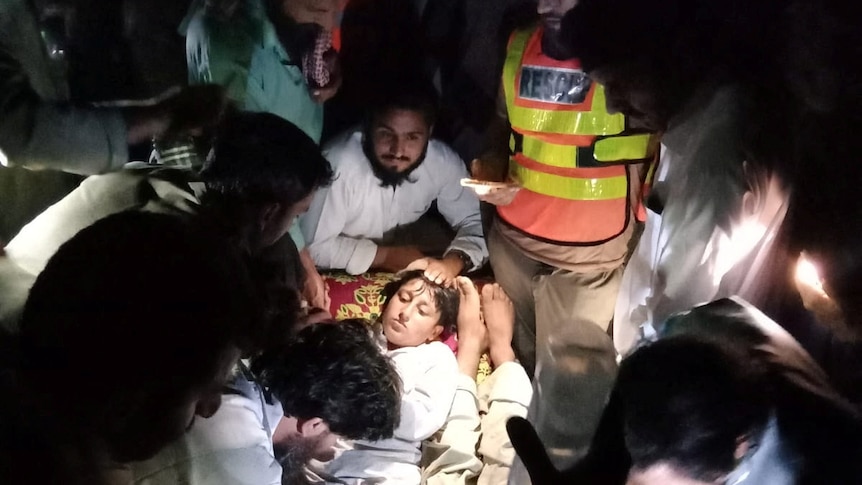 People gathered around two children giving medical assistance in the dark
