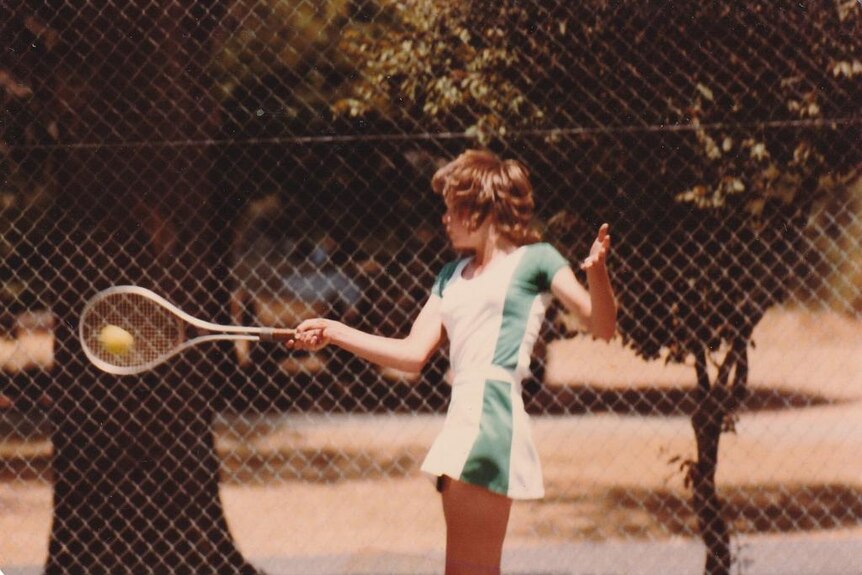 A photograph scan of a girl about age 10 playing tennis wearing a green skirt