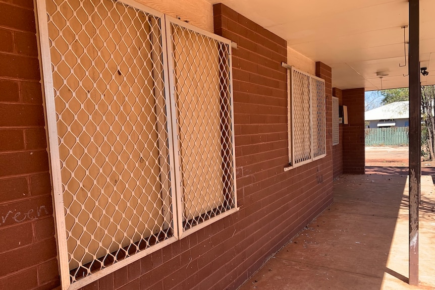 A brick house with boarded up windows.