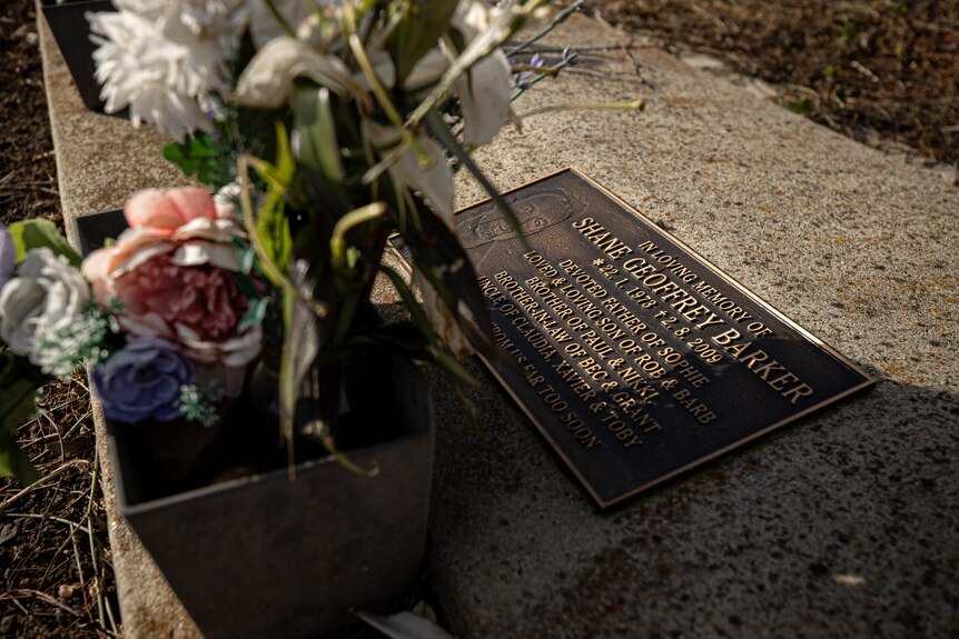 Flowers sit on a headstone which reads: In loving memory of Shane Geoffrey Barker