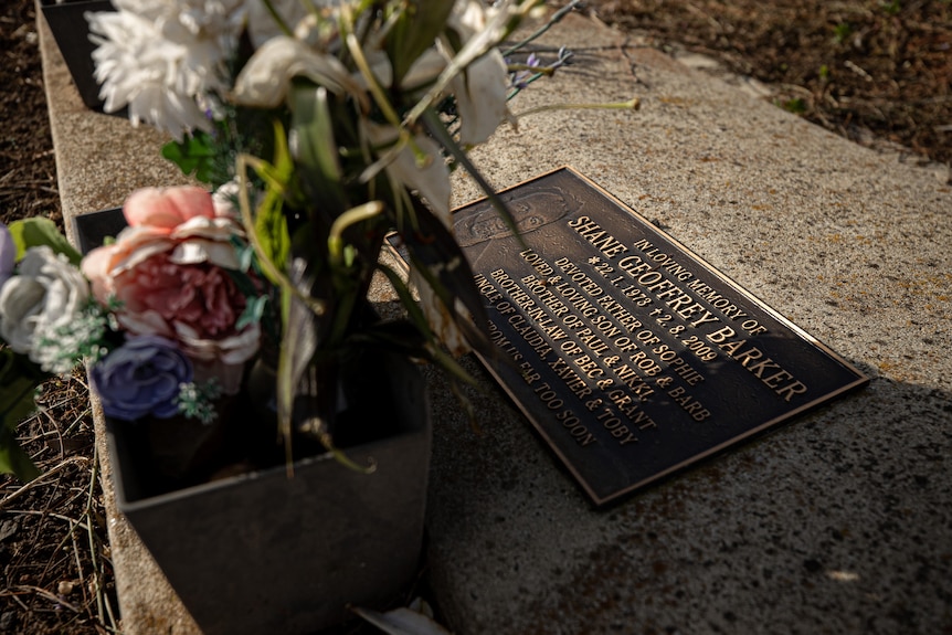 Flowers sit on a headstone which reads: In loving memory of Shane Geoffrey Barker