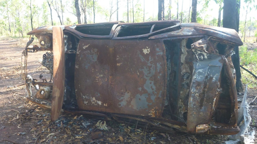 A burnt out car lying on its side in Darwin's rural area.