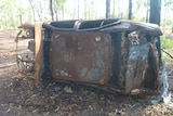 A burnt out car lying on its side in Darwin's rural area.