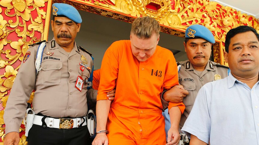 Police officers escort Australian national David van Iersel to a press conference in Bali.