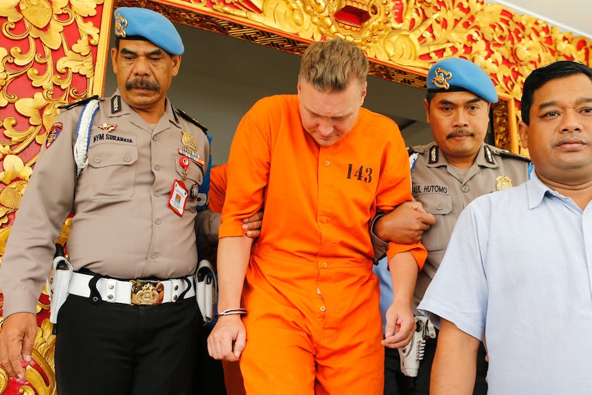 Police officers escort Australian national David van Iersel to a press conference in Bali.