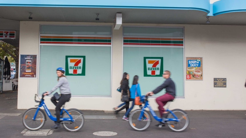 Bike riders passing a 7-Eleven store