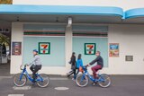 Bike riders passing a 7-Eleven store