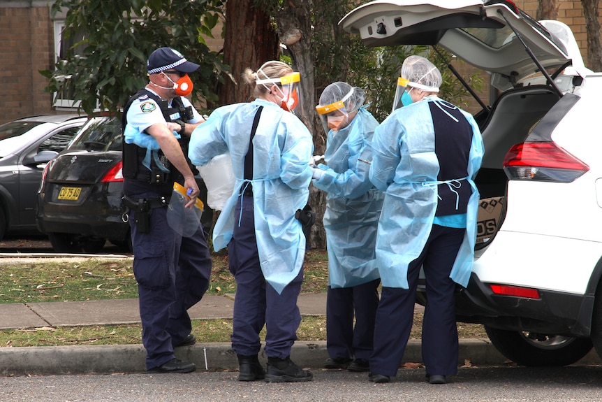 Health care workers prepare to enter a block of units