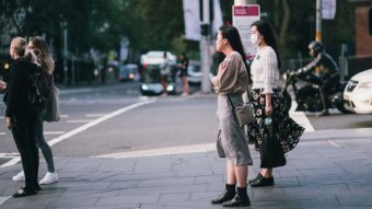 Women standing at a light on a street in Sydney.