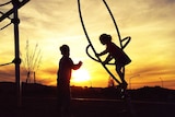 Two children playing in a play ground at sunset