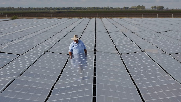 A person standing in the middle a large solar plant.