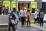 People disembarking a tram in Melbourne, many of whom are wearing masks.