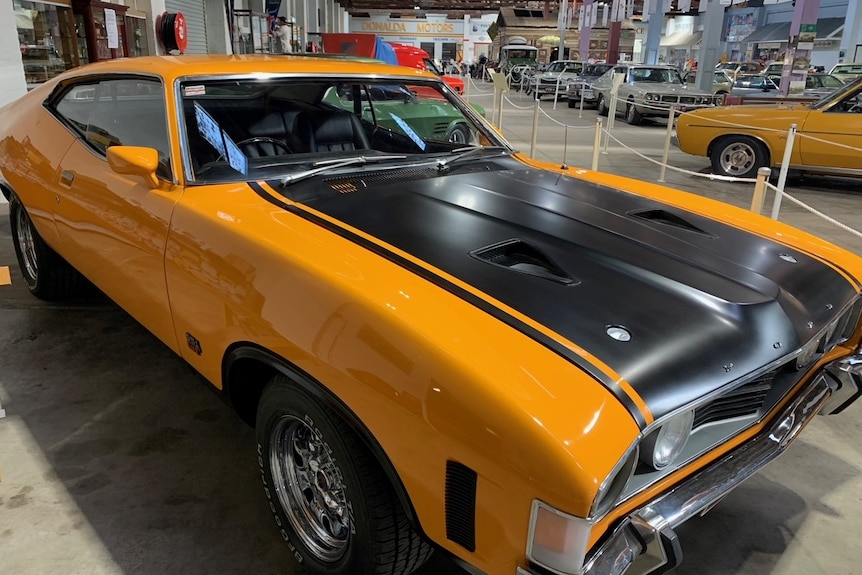 bright orange sports striped coupe car in a museum.