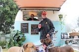 A customer and their dogs stands outside Chevelle Salis' coffee trailer.