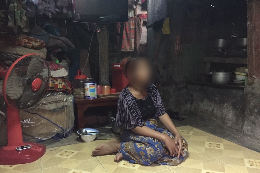 Chan Nareth sits on the floor of her house.