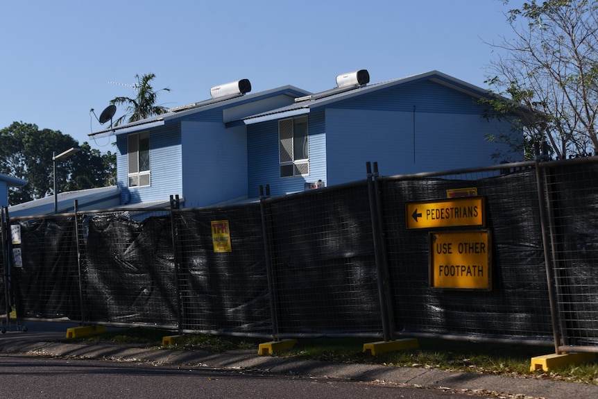 Some blue public housing units with construction fencing on the outside.