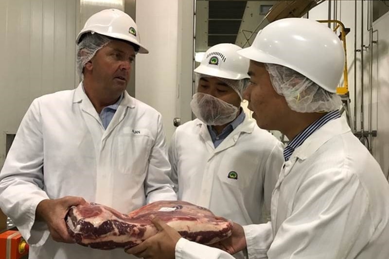 Chinese businessmen Ming Yang and Wong Sheng with Alan Kropp from Australian Country Choice holding a cut of beef.