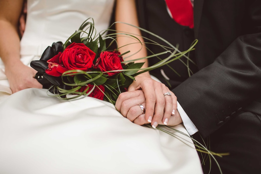 Newly weds with red rose bouquet.