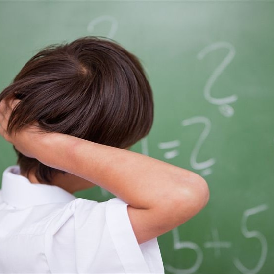 A child looking at a blackboard with his back to the camera