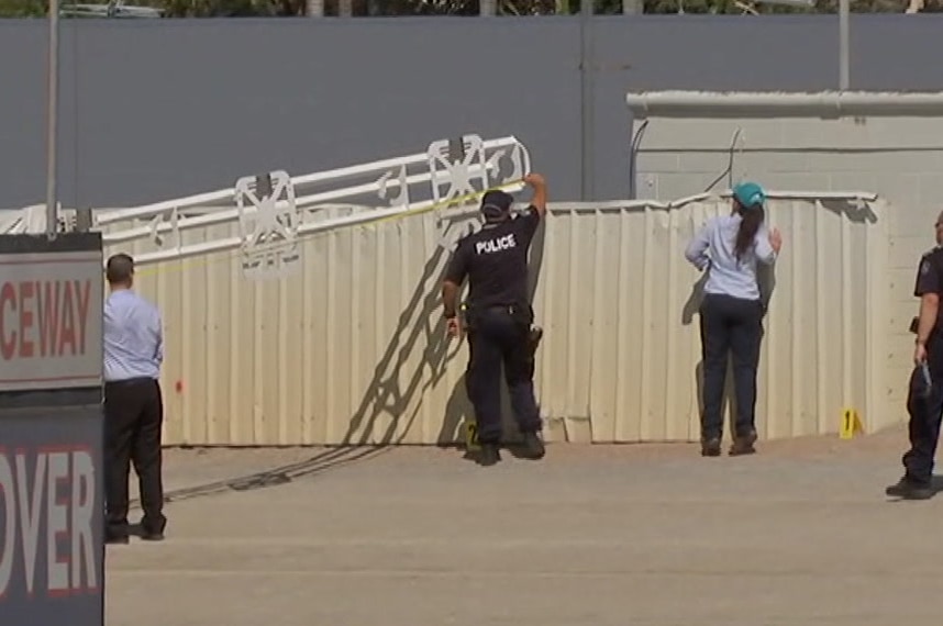 A police officer stretches a measuring tape along a boom gate.