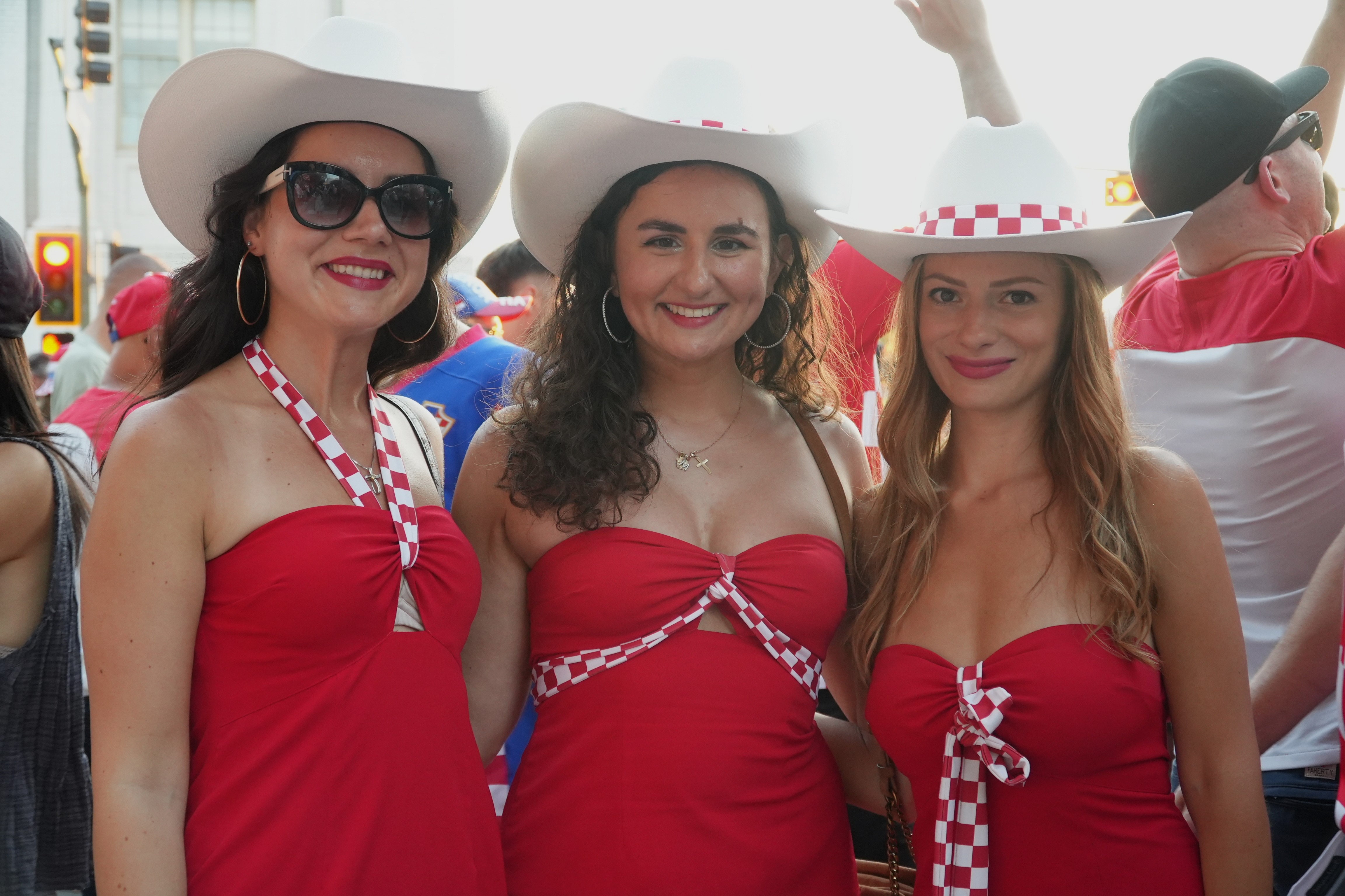 Three young women wearing cowboy hats and red strapless dresses