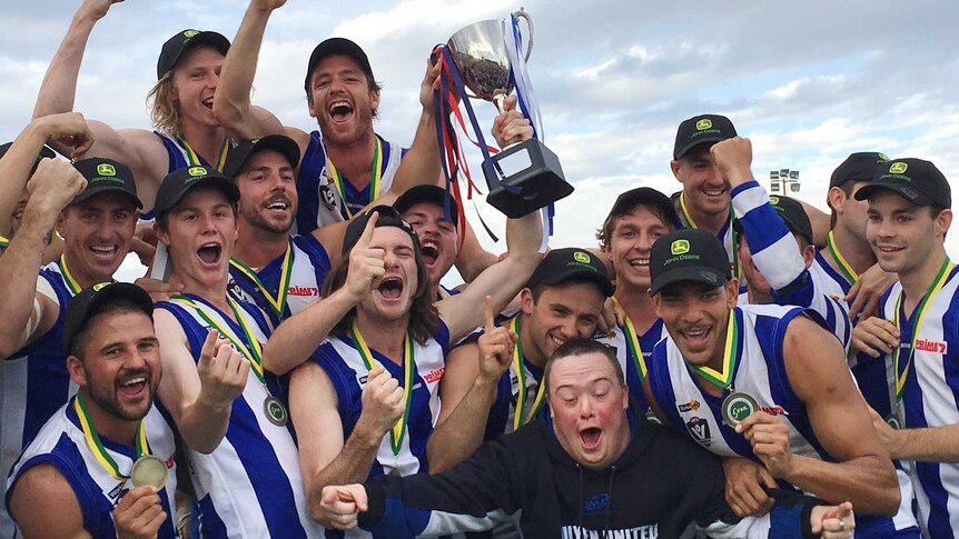 a group of Ouyen United foootballers wearing medals celebrating a premiership.
