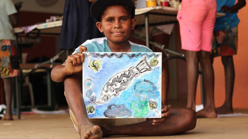 A young boy with a colourful painting.