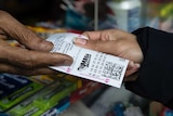 A close-up of a vendor selling a lottery ticket.