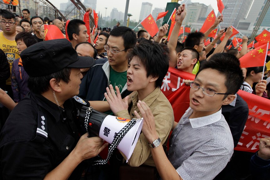 A paramilitary policeman with a loud hailer tries to maintain order among the protesters in Chengdu.