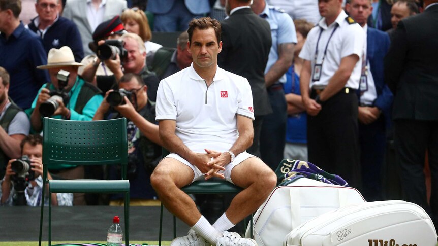Roger Federer looks exhausted sitting in the player's chair after losing the Wimbledon men's final