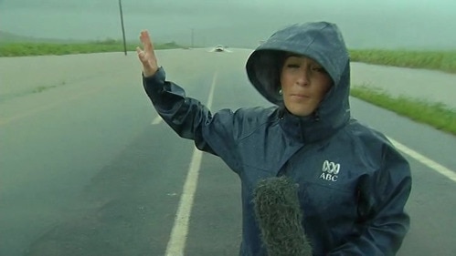 Allyson Horn stands in the elements, recording an 'As Live' report from the flooded Bruce Highway