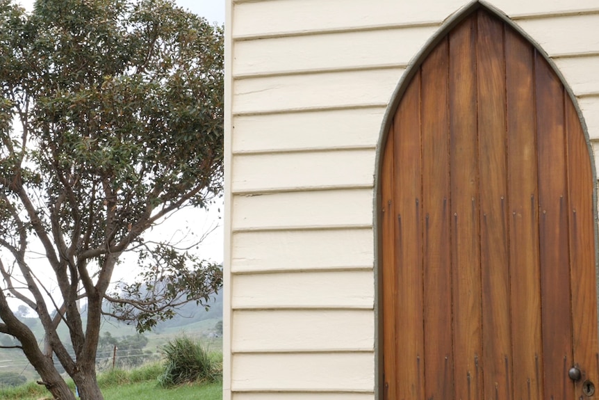 A church door in a timber church with a tree in the background