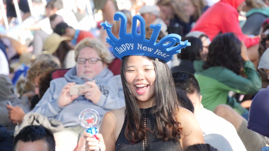 One reveller wears a novelty 2016 hat while waiting among crowds for the fireworks on Sydney Harbour