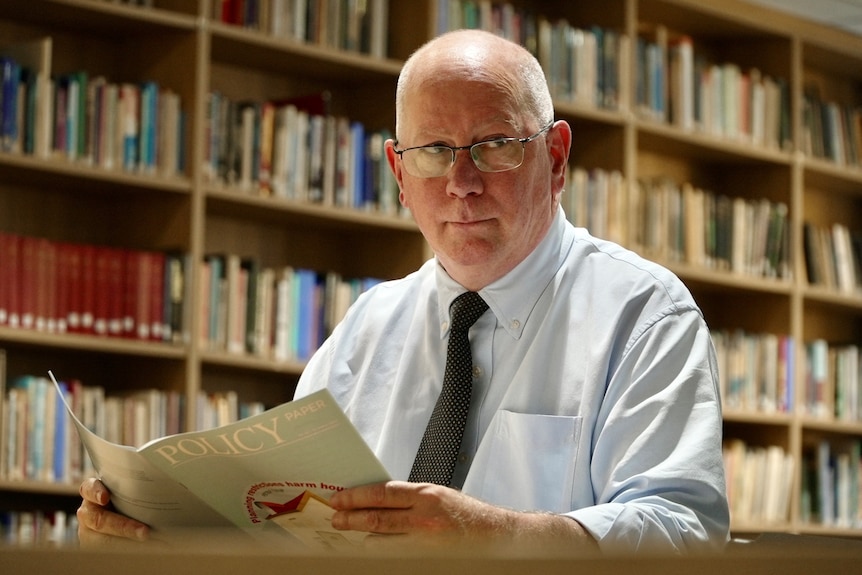 Peter sitting in front of bookshelves in his Sydney CBD office.