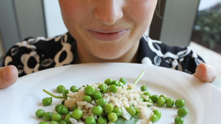 A person smells food on a white plate.