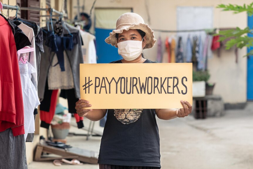 A Cambodian woman holds a sign reading "Pay your workers".