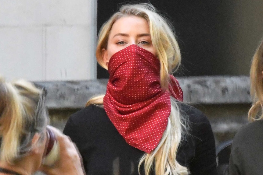 Amber Heard, wearing a red scarf over her mouth for protection arrives outside London's High Court.