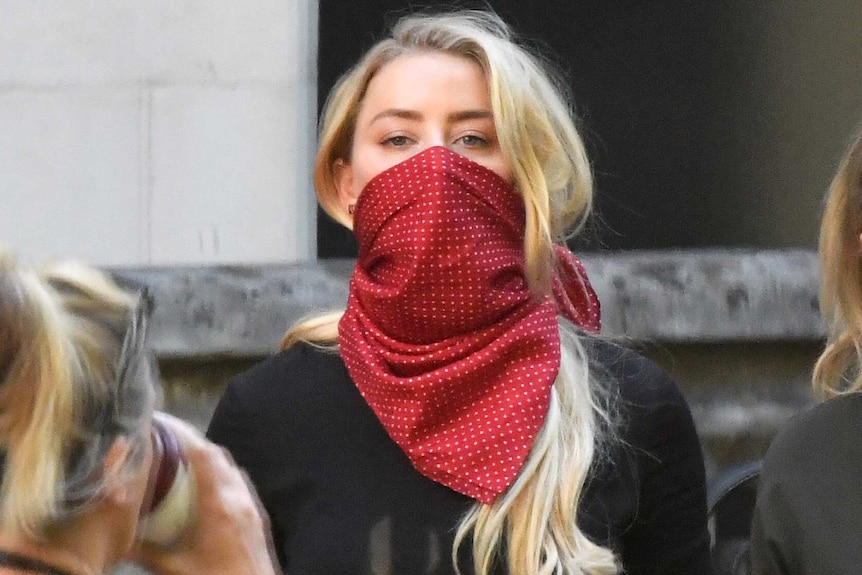 Amber Heard, wearing a red scarf over her mouth for protection, arrives outside London's High Court.