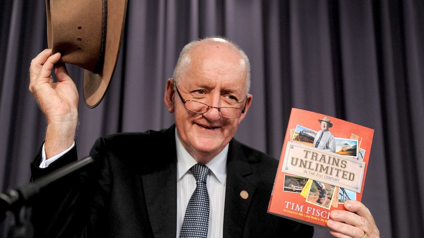 Tim Fischer smiles as he holds up his Akubra hat and a copy of his book, Trains Unlimited.