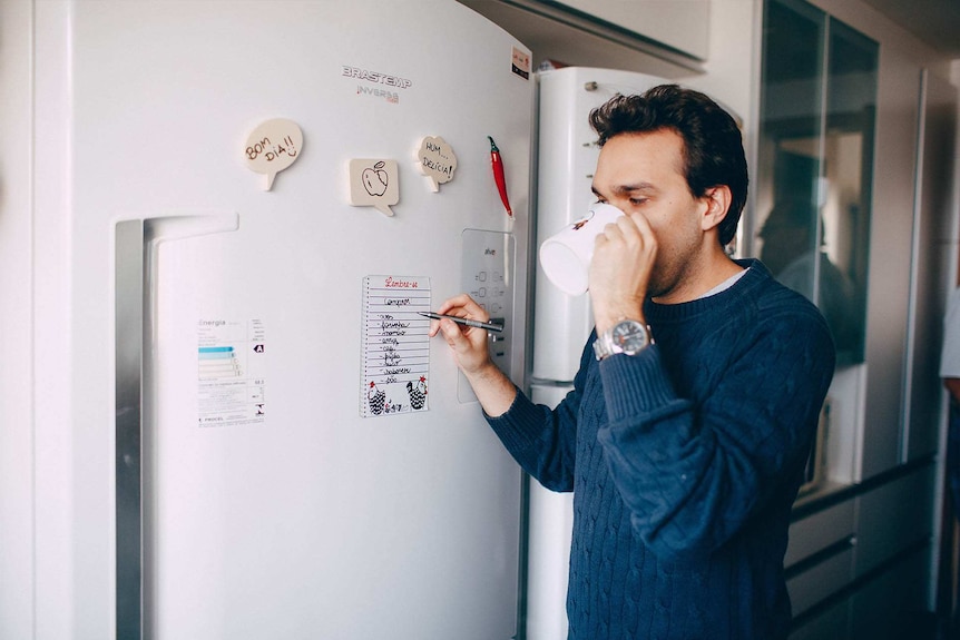 Man making lists on his fridge to stay organised